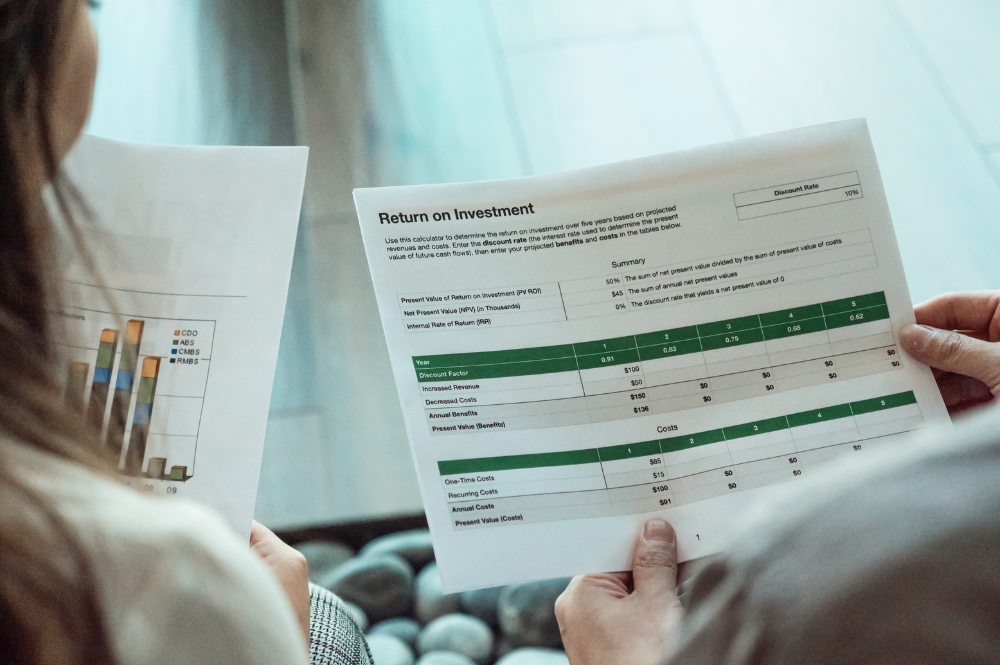Two individuals analyzing papers with graphs, discussing a diversified investment portfolio strategy.